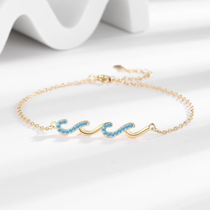 Elegant gold-plated wave bracelet for women featuring vibrant blue rhinestones on a white base