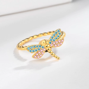 Rotating dragonfly ring with blue and pink zircons on a gold twisted rope band