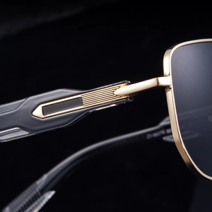 Macro shot of gold metal sunglass hinge with precise striped details and dark lenses