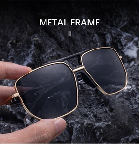 Close-up of golden metal frame sunglasses with double bridge and dark lenses on rock