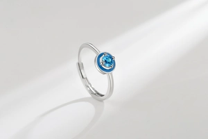 Macro shot of silver ring with round light blue gemstone and dark blue enamel detail