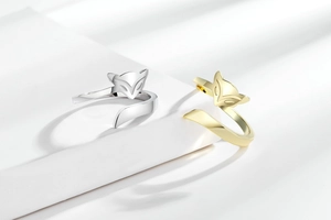 Detailed close-up of fox-shaped wrap rings in gold and silver finish on a white stand