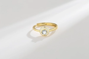 Macro detail of adjustable gold ring with white enamel and sparkling round moissanite