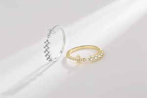 Detail of cross and round zirconia stones on gold and silver open rings
