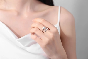 Close-up of a minimalist silver fox open ring worn on a finger with a silk dress