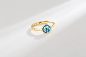 Macro shot of gold adjustable ring featuring blue enamel devil eye and round crystal