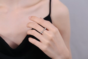 Detailed view of silver cross ring with zircons worn on model's finger with black outfit