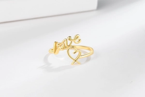 Détail du lettrage LOVE doré et du design en cœur sur une bague ouverte minimaliste