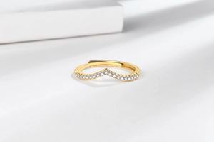 Macro shot of V-shaped gold ring featuring micro-pave crystals on an open band