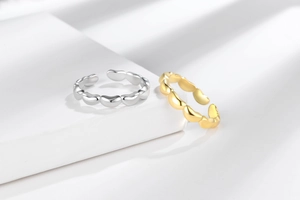 Detail von ineinandergreifenden Herzringen in Gold und Silber auf strukturiertem Grund
