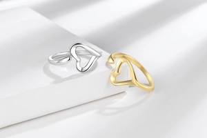 Detailed view of silver and gold heart-shaped open rings with a polished mirror finish