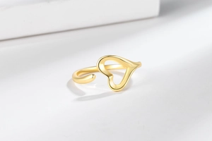 Close-up of golden heart-shaped open ring with high-polish finish on marble surface