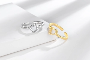 Detailed close-up of gold and silver heart-shaped adjustable open rings on a pedestal