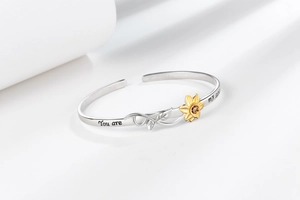 Detail of silver cuff bracelet showing sunflower inlay and 'You are my sunshine' engraving
