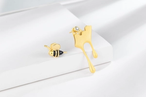 Asymmetric bee earrings featuring a gold bee and fluid drop with a clear zircon stone