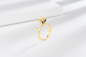 Detailed view of adjustable golden bee ring with vine band on white pedestal