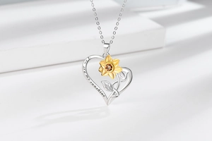 Detailed view of silver heart pendant engraved with You Are My Sunshine and gold sunflower