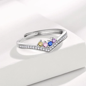 Close-up of V-shaped silver ring with colorful zircons on a white geometric stand