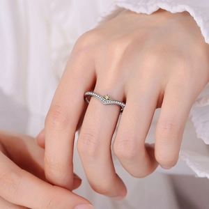 Macro shot of V-shaped silver ring with white zircons and yellow gemstone on finger