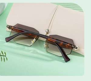 Detail of gradient brown rimless sunglasses with leopard print arms on green silk fabric