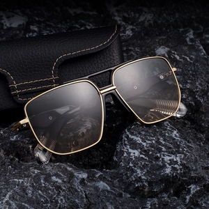 Modern square black and gold sunglasses with protective case on a dark stone background