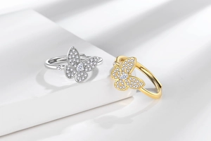 Macro shot of silver and gold butterfly rings with inlaid zircons on a white podium
