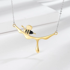 Modern silver necklace with a unique gold honey drip pendant and a detailed bee accent