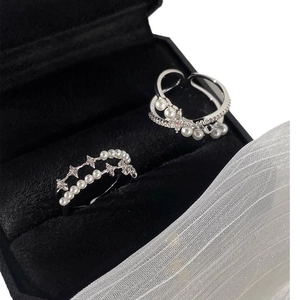 Detail of silver double-layer rings with white pearls and star crystals on black velvet