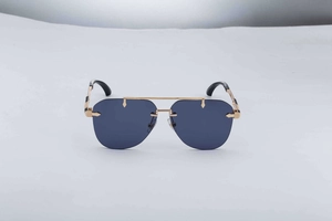 Close-up of golden metal hinges with intricate engraved patterns on rimless sunglasses