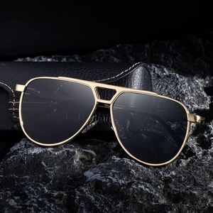 Classic gold aviator sunglasses for men with dark lenses and black leather case on rocks