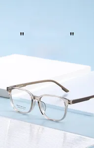 Detail view of champagne square eyeglass frames with metallic hinges and branded temples