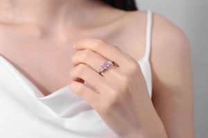 Nahaufnahme eines Rings mit rosa ovalem Edelstein am Finger bei weichem Licht