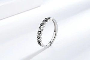Macro shot of silver adjustable ring featuring carved Chinese luck symbols on coin patterns