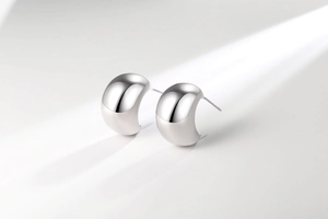 Macro shot of silver C-shaped chunky earrings with mirror polished metallic finish