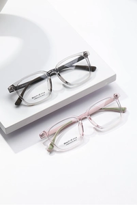 Detail van vierkante optische monturen in transparant grijs en roze met maatparameters
