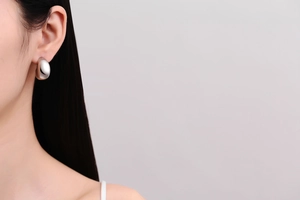 Close-up of minimalist silver drop earrings with high-polish finish on a model