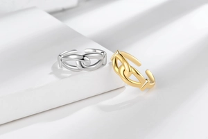 Detailed view of gold and silver knot chain link rings on minimalist white stone