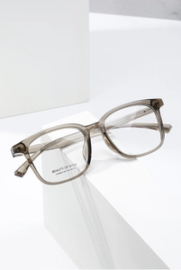 Detailed side view of stylish tea-grey square frame glasses on white display stand