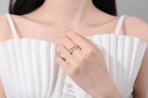 Detail of silver 'love' letter ring on model's finger with adjustable open band design