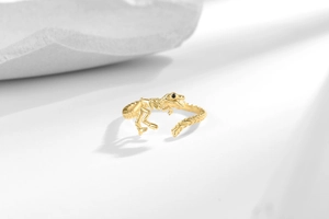 Detail of golden dinosaur skeleton ring featuring realistic bone structure and black gem eyes