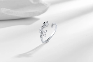 Macro shot of silver dinosaur skeleton open ring showing detailed carving on white background