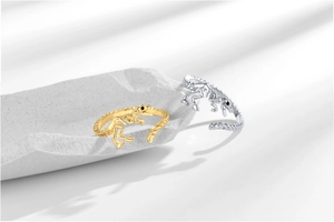 Detail view of gold and silver dinosaur skeleton rings on grey stone props