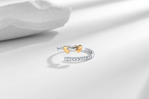 Macro shot of silver open ring with dual gold hearts and micro-paved cubic zirconia stones