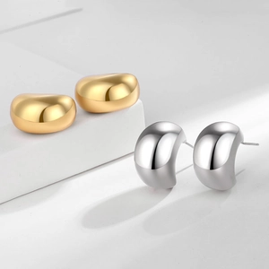 Minimalist 18K gold and silver hollow C-shape earrings on geometric display stand