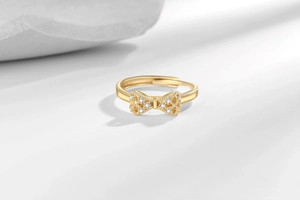 Macro detail of golden bow ring featuring sparkling zircon inlay and textured beads