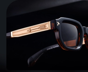 Macro detail of glossy black acetate sunglasses with vintage gold arrow metal inlay temples