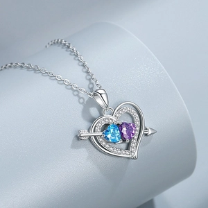 Macro view of Cupid's arrow necklace with interlocking double hearts and colorful stones