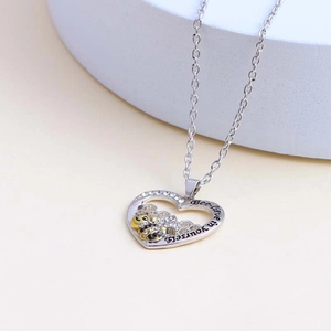 Detailed close-up of heart pendant with bee motif and Bee-lieve in yourself engraving