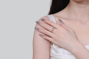 Close-up of a silver adjustable rainbow heart ring worn on a finger with colorful enamel