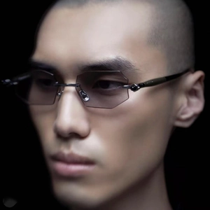 Detail of rimless octagonal sunglasses with dark lenses and gunmetal bridge on model